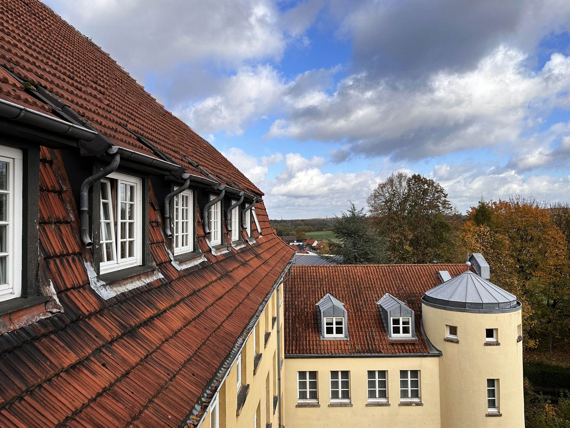 Der Blick aus dem Dachgeschoss von Haus Ohrbeck zeigt einen Herbsthimmel mit dicken, dunklen Wolken, die über einen blauen Himmel ziehen.